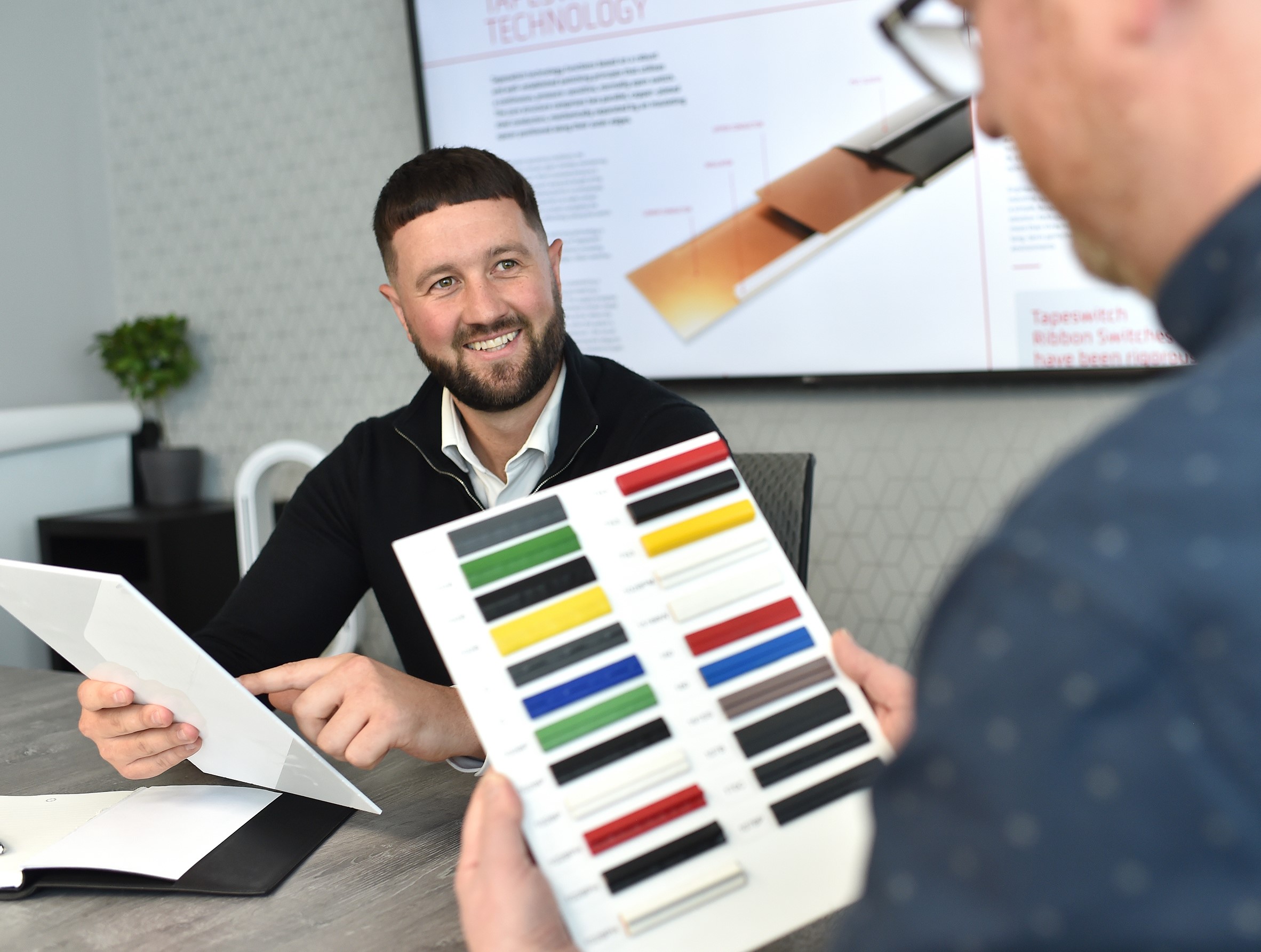 Blake Shields of Tapeswitch showing a client a colour swatch board of pressure-sensitive safety products